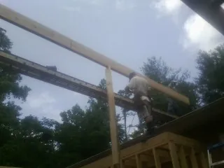 Carpenter setting a ridge beam over a new addition frame — Ice Dam Removal by Roofing Brothers in Nickelsville