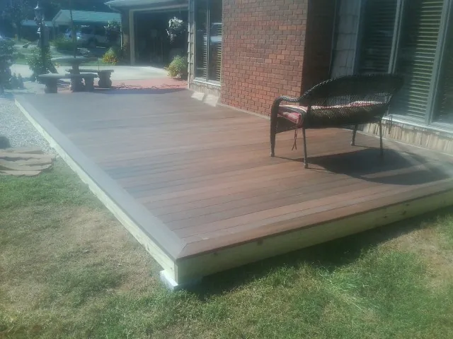 New wood deck and wicker chair beside a brick house in Nickelsville