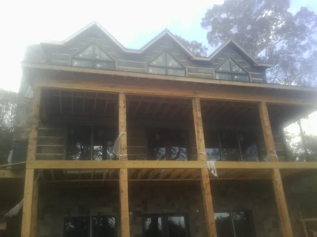 Dormers and porch framing on a large log home under construction — Roof Coating work by our crew in Nickelsville