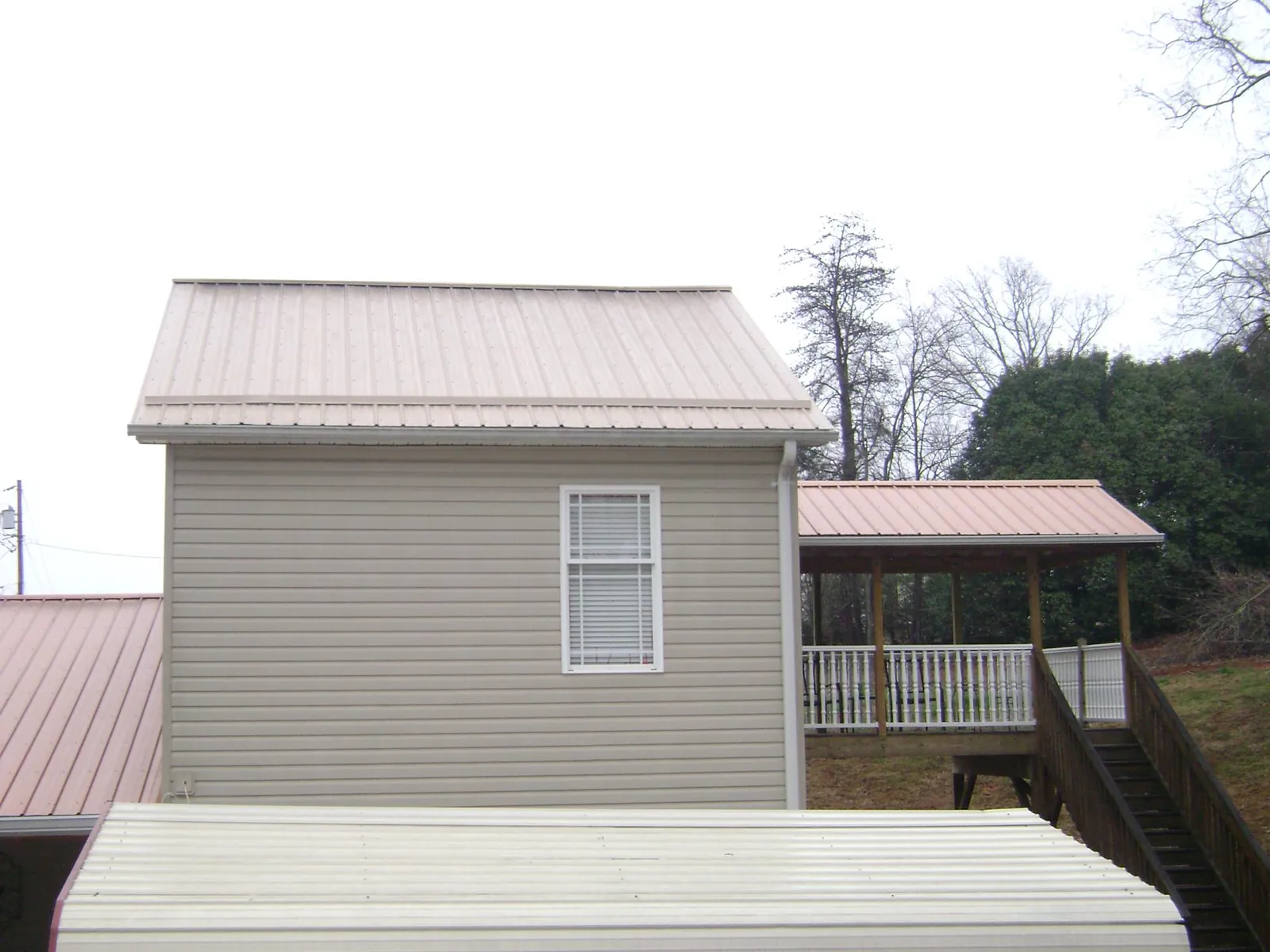 Tan metal roofs on a two story addition and attached porch, from a Roof Replacement job in Nickelsville